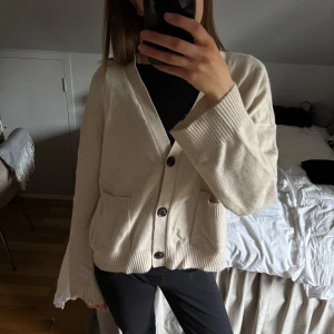 Beige kofta med knappar -  stilren beige kofta med knappar framtill.