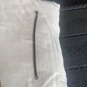 Svart kedjearmband - Stilrent svart armband med tunn kedja och karbinlås. Armbandet är i nytt skick, armbandet är gjord av stål, 18cm lång, 50kr
