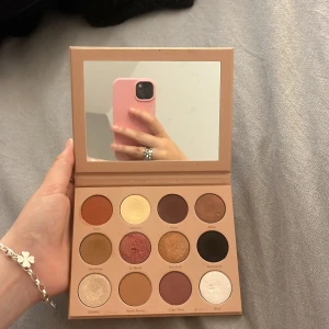 CAIA ögonskuggspalett med spegel - Säljer en CAIA ögonskuggspalett med 12 nyanser i både matta och skimriga toner. Färgerna går i brunt, guld, rött, svart och champagne. Paletten har en inbyggd spegel och är i snygg beige förpackning. Perfekt för att skapa olika looks med både neutrala och mer färgstarka skuggor. Köptes för 599 kr men säljer för endast 299 kr. 