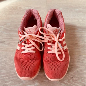 Adidas löparskor/sneakers  - Adidas löparskor/sneakers, Storlek 38 (US 7 ½), Äkta vara i fint skick!
 Autentiska Adidas-skor – sparsamt använda och välvårdade.
 Lätta, bekväma och andas väl – passar utmärkt för både träning och vardagsbruk.
 Fräsch korallröd färg med klassisk design och Adidas-kvalitet.
 Finns för upphämtning i Kista, Stockholm eller leverans enligt överenskommelse.

