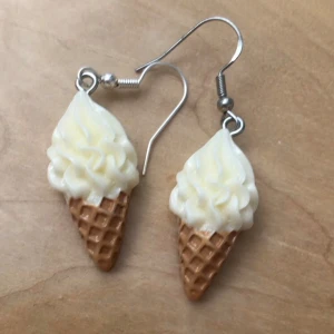 Glassörhängen i form av strut - Roliga örhängen formade som glassar i strut med vit glass och ljusbrun våffla. Perfekta för dig som vill sticka ut och addera en lekfull touch till din stil. Hängande modell med metallkrok. Priset gäller för ett par örhängen (de i bilden) men det finns 3 par i lager (de i bilden inkluderade) så man kan köpa alla tre för 20kr💞