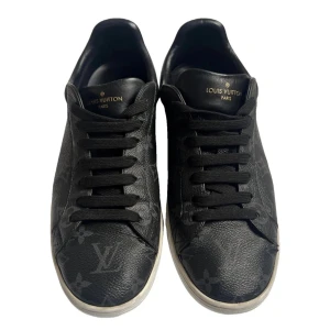 Svarta sneakers från Louis Vuitton - Snygga svarta sneakers från Louis Vuitton med monogrammönster. Skorna har snörning och en vit sula med diskreta detaljer. Perfekta för en stilren look. Autenticitet bevis finns!