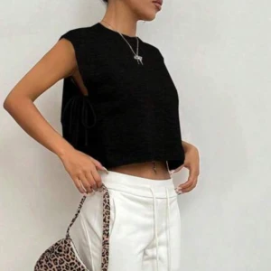 Svart croppad stickad topp/väst  - En jätte snygg  svart croppad stickad topp/väst den har öppna sidor som knyts som du kan se på bilden. skönt material, den är M men passar S och M. 