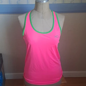 Neonrosa linnetopp  - Sportig neonrosa linnetopp från Kari Traa med gröna kantband och grå meshpanel i ryggen. Skick enligt bilder . 🩷 Str XL men lite liten i storleken 