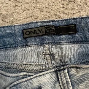 Ljusblå jeanskjol från ONLY - Ljusblå jeanskjol från ONLY med slitna detaljer, klassiska fickor både fram och bak samt dragkedja i sidan. Kjolen har bälteshällor och en snygg, kort passform.