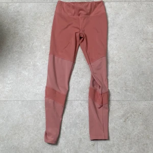 Rosa leggings från OTP Young - Säljer ett par snygga rosa leggings från OTP Young i storlek 146/152. De har paneler i olika nyanser av rosa och sitter tight med hög midja. Perfekta för träning eller chill, tillverkade i stretchigt syntetmaterial som andas.