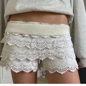 Vita virkade shorts med volang och spets - Superfina vita shorts med bred resår i midjan och flera lager volang i virkad spets. De har en romantisk och bohemisk känsla med snyggt mönster och scallop-kant. Perfekta för varma dagar när du vill sticka ut lite extra.Man viker ner dem i kanten.💗de är kräm vita. Skriv för funderingar❤️
