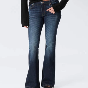 Lågmidjade jeans som är flared - Mörkblå jeans som är flared i passform och klassisk femficksdesign. Jeansen har snygga slitningar och kontrastsömmar, tillverkade i robust denim. Perfekta för dig som gillar en retrovibe och vill ha ett par jeans med lite extra vidd nertill. Storleken är W28 och L32
