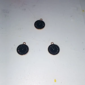 Svarta klockhänge till halsband - Tre runda svarta hängen med klockmotiv och romerska siffror i vitt. Perfekta som unika detaljer till halsband eller armband. Kan kombineras med kedja för en personlig stil. Metallkant i guldton ger en snygg kontrast.