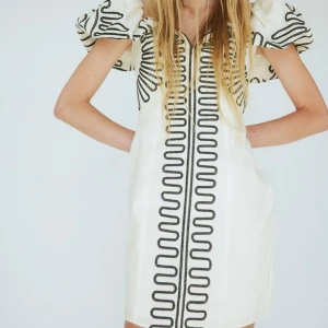 Vit kortklänning med puffärmar - Superunik vit kortklänning med svarta broderade detaljer och stora puffärmar. Klänningen köptes förra sommaren för helpris 699kr! Och endast kommit till användning 1 gång! Därav säljes för 450kr🌸🌸