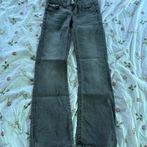 Grå bootcut jeans från Gina Young - Snygga grå jeans från Gina  Young  i storlek 152. Modellen har bootcut-ben och klassisk femficksdesign. Jeansen är tillverkade i mjukt denimtyg och har silverfärgade knappar framtill. Perfekta för en cool och avslappnad look.