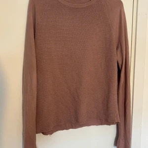 Rosa ribbad stickad tröja - Mysig rosa stickad tröja med ribbad struktur på framsidan. Tröjan har rund halsringning och långa ärmar. Perfekt för lager-på-lager och chill dagar. Enkel och stilren design som funkar till det mesta.