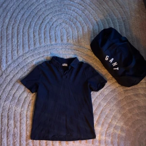 Mörkblå pikétröja These Glory Days - Snygg mörkblå pikétröja från These Glory Days i storlek Large. Klassisk krage med knappar och korta ärmar. Perfekt för en clean och stilren look. Tillverkad i mjuk bomull som känns skön mot huden.