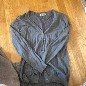 Grå kofta från Canard Collection S - Mysig grå kofta från Canard Collection i storlek S. Klassisk modell med v-ringning, långa ärmar och knappar framtill. Tillverkad i mjukt material med ribbade muddar vid ärmslut och nederkant. Perfekt att slänga över en t-shirt eller linne. (Fläckarna är vatten)