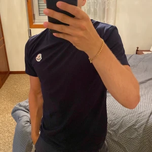 Mörkblå Moncler t-shirt i bomull - Snygg mörkblå t-shirt från Moncler med klassisk passform och rund hals. T-shirten har ett broderat Moncler-märke på bröstet och är gjord i mjuk bomull. Perfekt för dig som gillar stilrena och exklusiva plagg. (Pris kan diskuteras)