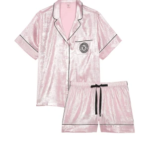 Glittriga rosa pyjamasshorts med snörning ifrån Victoria secret  - Snygga glittriga rosa pyjamasshorts från Victoria's Secret med svart snörning i midjan och svarta detaljer längs kanterna. Mjukt och glansigt material som känns lyxigt mot huden. Perfekta för mysiga kvällar hemma.