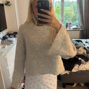 Ljusgrå stickad tröja med slits - Supermysig ljusgrå stickad tröja med breda ärmar och slits på sidorna. Tröjan har en grovstickad struktur och en rund halsringning. Perfekt för lager-på-lager och chill dagar. 💘