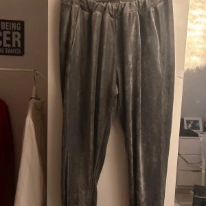 Grå mjukisbyxor från Boohoo - Supermjuka grå mjukisbyxor från Boohoo i sammet med elastisk midja och fickor. Byxorna har ribbade muddar med svarta och grå ränder nertill för en sportig vibe. Perfekta för chill dagar eller när du vill vara extra bekväm.