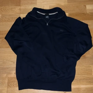 Quarter zip hugo boss - Snygg mörkblå tröja från BOSS med halv dragkedja och diskret broderad logga på bröstet. Tröjan har lång ärm, ribbade muddar och är tillverkad i mjukt stickat material. Perfekt för en stilren och avslappnad look.