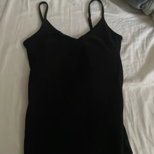 Lager 157 linne - Enkel och stilren svart linne från lager 157, med smala axelband och figurnära passform. Linnet har en v-ringad urringning och är ärmlös, perfekt för dig som gillar minimalistisk stil. Passar dig som vill ha en klassisk look med edge.