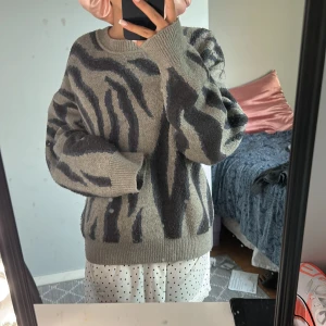 Zebramönstrad stickad tröja NA-KD - Säljer en stickad tröja från NA-KD i storlek S med grått och svart zebramönster. Tröjan har rund halsringning, långa ärmar och en loose fit som ger en chill vibe. Perfekt för dig som vill sticka ut lite extra i höst och vinter.