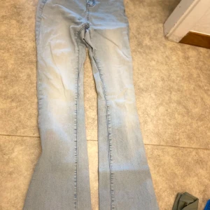 Ljusblå bootcut jeans - Säljer ett par ljusblå jeans med bootcut-modell. Jeansen har klassisk femficksdesign och är tillverkade i mjukt denimtyg. Perfekta för dig som gillar retrovibbar och vill ha en snygg siluett med utsvängda ben.