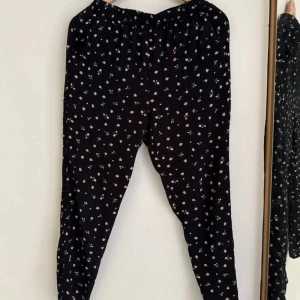 Svarta blommiga byxor med resår - Svarta byxor med små rosa blommor och elastisk midja. Lätta och luftiga, perfekta för en chill och avslappnad stil. 