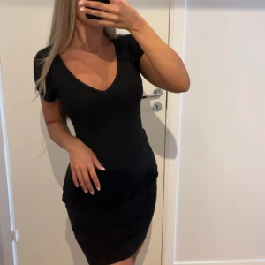 Svart ribbad Body - Snygg svart ribbad Body från IRIS med v-ringning och korta ärmar. HELT OANVÄND!