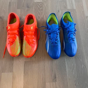 Adidas och Puma fotbollsskor - Två par fotbollsskor: ett par Adidas i neonrött med gröna detaljer och snörning, samt ett par Puma i blått med vita och limegröna detaljer, snörning och dobbar.  Puma skorna 600kr och Adidasbyxor 200kr. Paketpris 500kr