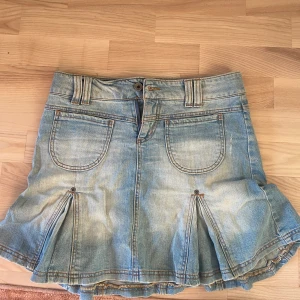 Lågmidjad jeans kjol - Snygg ljusblå jeanskjol från Only Jeans med coola fickor både fram och bak, samt markerade sömmar och veckade detaljer nertill. Kjolen har bälteshällor och knappstängning framtill. Perfekt för dig som gillar en avslappnad och trendig stil.