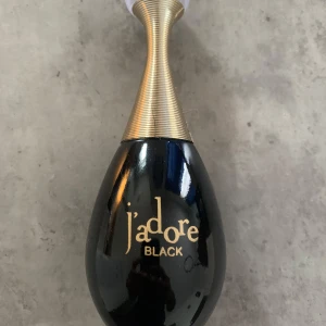 J'adore Black parfymflaska - Snygg parfymflaska från J'adore Black med elegant svart och guldig design. Flaskan har en droppformad kropp i svart glas och ett smalt, guldigt halsstycke med en rund, transparent kork. Perfekt för dig som gillar lyxiga och stilrena detaljer på sminkbordet. ‼️‼️Det finns ingen kartong ‼️‼️‼️