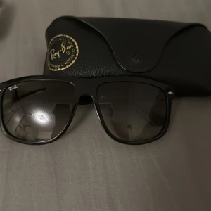 Rayban boyfriend - Snygga svarta Ray-Ban boyfriend solglasögon med klassisk fyrkantig form och mörka glas. Bågarna är i blank svart plast och har Ray-Ban-loggan på sidan. Perfekta för att lyfta din stil under soliga dagar. Fodral i svart medföljer. Kan byta mot andra glasögon eller boyfriends i mindre storlek