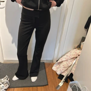 Svarta kostymbyxor ifrån gina!  - Snygga svarta byxor med bootcut-ben och hög midja. Byxorna har en bred linning med dekorativ detalj framtill och är sydda i ett stretchigt material som sitter bekvämt. Perfekta för en trendig och stilren look. Storlek Xs, använda fåtalgånger. Nyskick!