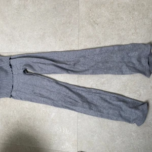 Grå stickade byxor från Gina Tricot - Mysiga grå stickade byxor från Gina Tricot med bred ribbad midja och raka ben. Perfekta för chill dagar hemma eller när du vill vara extra bekväm. Mjukt material som känns skönt mot huden och ger en avslappnad vibe.