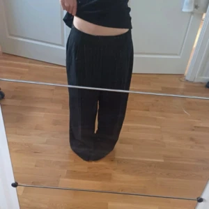 Svarta randiga kostymbyxor wide fit - Säljer ett par svarta kostymbyxor med tunna vita ränder. 