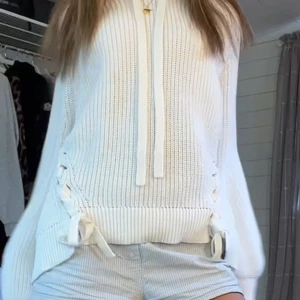  stickad hoodie med snörning från hm - Superfin vit stickad hoodie med långa ärmar och snygga snörningsdetaljer i sidorna. Tröjan har ribbade muddar och dragsko i halsen för en chill vibe. Perfekt till jeans eller shorts för en avslappnad look.