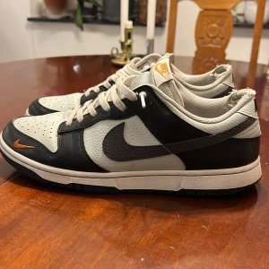 Nike Dunk i svart och blå/blågrå - Snygga Nike Dunk sneakers i svart och grått med vita detaljer. Skorna har en klassisk design med snörning och den ikoniska Nike-loggan på sidan. Perfekta för en stilren look. Nypris: 1399