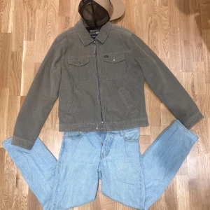 Olivegrön overshirt i Manchester från RVCA - Säljer en snygg olivgrön overshirt i manchester från RVCA. Jackan har en dragkedja framtill och två bröstfickor med knappar. Insidan är fodrad med ett svartvitt rutigt mönster i fleece. Perfekt för kommande våren! Nypris 1800, köpt i Frankrike 🇫🇷!