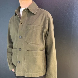 H&M, overshirt - Snygg olivgrön overshirt med knappar framtill och stora fickor. Perfekt för lager-på-lager-stil. Den har en klassisk krage och långa ärmar.