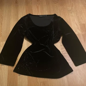 Svart sammetstopp från KappAhl - Elegant svart sammetstopp från KappAhl (gammal kollektion) med glittrande detaljer i form av mönster. Toppen har lite kortare ärmar typ trekvarts. Mycket bra skick. Storleken motsvarar S. 