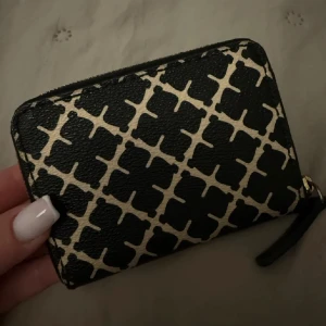 Malene birger plånbok - Snygg plånbok i svart och beige med ett unikt mönster. Den har en praktisk dragkedja och är perfekt för att hålla dina kort och kontanter säkra. En stilren accessoar som passar i alla väskor. Nyskick nästan aldrig använd 