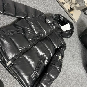 Svart Moncler maya  - Säljer en snygg svart pufferjacka från Moncler. Jackan har en glansig finish och är utrustad med en dragkedja framtill. Perfekt för kyliga dagar med sin vadderade design. Den har långa ärmar och en praktisk huva. Finns alla stor leksaker 