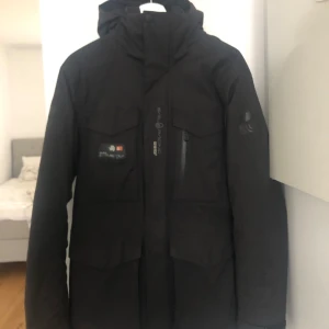 Sail Racing Glacier Bay Parka  - Säljer en svart Glacier Bay Parka från Sail Racing i storlek S. Det är en liten svart plast/tejpbit på högerarm som man inte lägger märke till. 