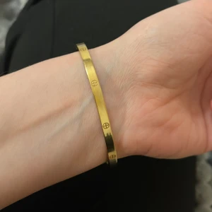 Guldarmband med skruvmönster - Elegant guldarmband med ett stilrent skruvmönster runt om. Perfekt för att ge en lyxig touch till din outfit. Armbandet har en slät och polerad yta som reflekterar ljuset vackert.