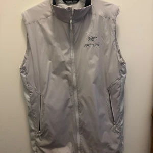 Arc'teryx Atom väst - Säljer en stilren ljusgrå väst från Arc'teryx med dragkedja framtill. Västen har en hög krage och två praktiska fickor med dragkedja. Perfekt för lager-på-lager. Nypris ca 2000kr. Mitt pris 600kr