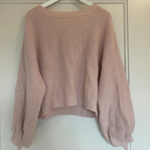 Ljusrosa stickad tröja med öppen rygg - Mysig ljusrosa stickad tröja med öppen rygg. Ärmarna är i ”balong” stuk. 