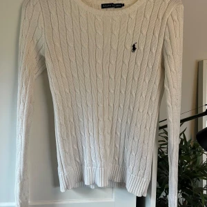 Vit stickad tröja från Ralph Lauren - Säljer en stilren vit stickad tröja från Ralph Lauren med kabelstickat mönster och den klassiska loggan broderad på bröstet. Tröjan har långa ärmar och en rund halsringning💕      Den är i storleken L men jag tycker mer den sitter som en M💗