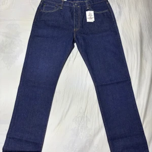 Levi's 501 Jeans Mörkblå - Klassiska Levi's 501 jeans i mörkblå denim med stretch. De har en knappgylf och femficksdesign. Perfekta för en tidlös stil.  Helt Oanvända!!