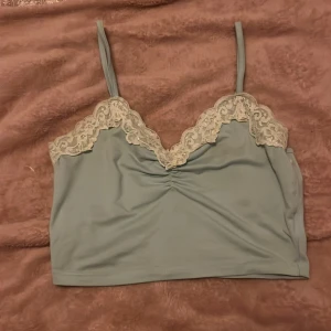 Ljusblå linnetopp med spetsdetaljer - Säljer en söt ljusblå linnetopp med smala axelband och vacker spetsdetalj längs urringningen. Den har inga märken och är perfekt för sommaren