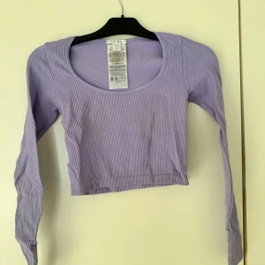 Lila ribbad topp från New Yorker - Snygg lila ribbad topp från New Yorker med långärmad design. Toppen är croppad och har en rund halsringning, perfekt för en trendig look. Tillverkad i ett mjukt och stretchigt material för extra komfort. Använd fåtal gånger och är sann i storlek. Skriv vid önskan om att se tröjan på💞